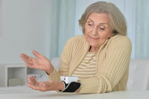 Smiling old woman using automatic carpal tonometer in hospital Stock Photos