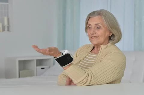 Smiling old woman using automatic carpal tonometer in hospital Stock Photos