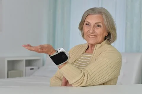Smiling old woman using automatic carpal tonometer in hospital Stock Photos