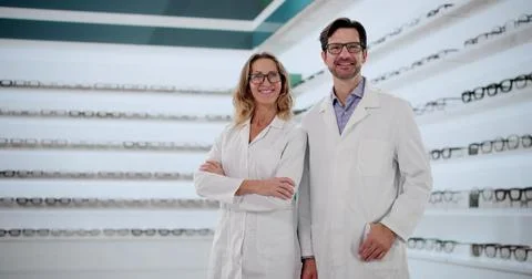 Smiling Opticians Help Customers Choose Stylish Eyeglasses In Optic Store. Stock Photos