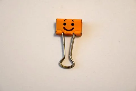 Smiling orange binder clip on a white background Stock Photos