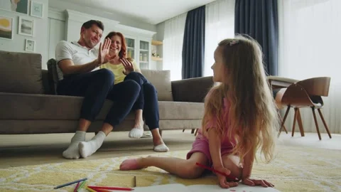 Smiling parents sit on the sofa in the hall romantically. The daughter Stock Footage 252609858