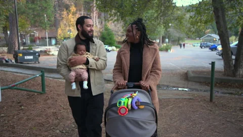 Smiling parents strolling with stroller while holding their newborn baby 스톡 동영상 324619850