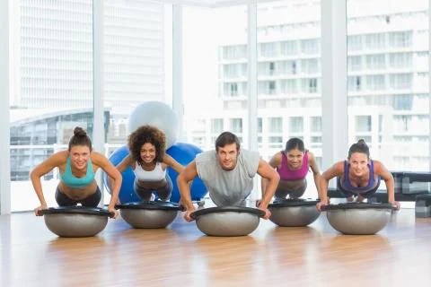 Smiling people doing push ups in fitness studio Stock Photos