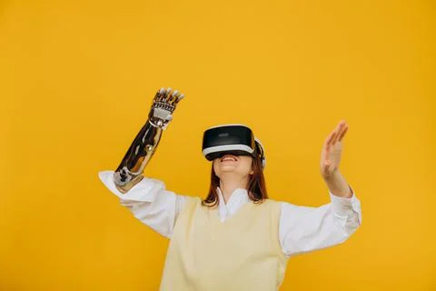 Smiling person with bionic arm and VR headset on yellow Stock Photos