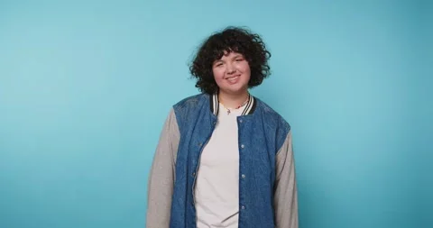 Smiling person poses in front of bright blue background while wearing casua.. Video stock 328247758