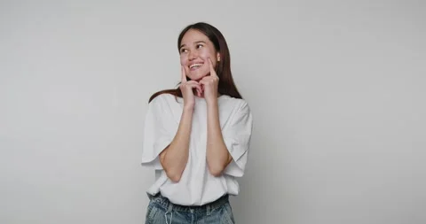 Smiling person shows different poses in indoor setting with plain backgroun.. 動画素材 328248482