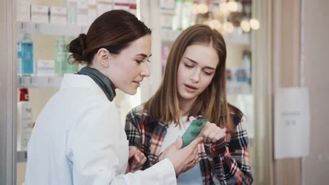 A smiling pharmacist consults a client about a product in pharmacy Stock Footage 156234368