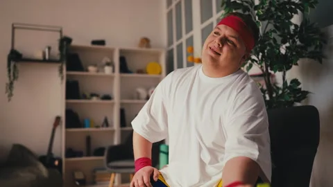 Smiling plus size man lifting dumbbells at home, home workout, training Stock Footage 249210909