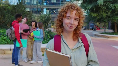 Smiling portrait of ginger student holding a binder on university campus Stock Footage 312203767