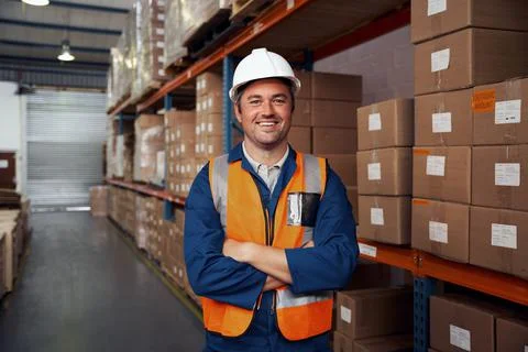 Smiling portrait of a warehouse worker in protective vest and white hardhat Stock Photos
