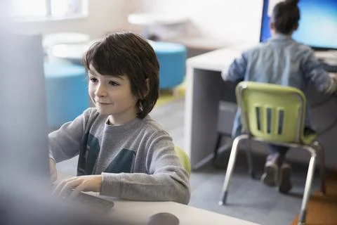 Smiling pre-adolescent boy using computer in classroom Stock Photos