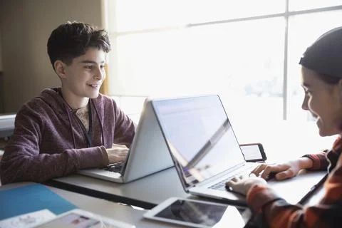 Smiling pre-adolescent boys using laptops in classroom Foto stock