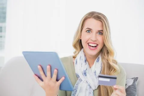 Smiling pretty blonde using her credit card to buy online Foto stock