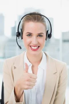 Smiling pretty call centre agent wearing headset giving thumbs up Stock Photos