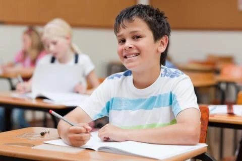 Smiling primary student sitting at desk Photos