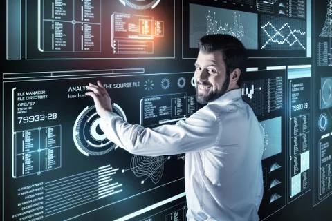 Smiling programmer touching the transparent screen while being at work Stock-Fotos