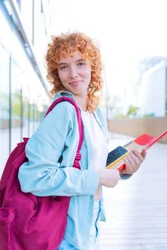 Smiling red-haired student with backpack and books outdoors.Vertical Stock Photos