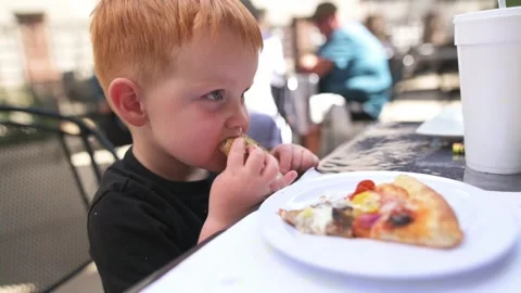Smiling red-haired toddler eating pizza with soda cup in background 스톡 동영상 320147340
