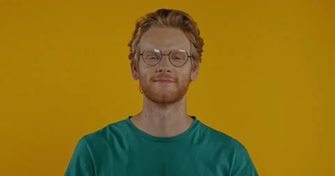 Smiling redhead man in glasses looking at camera isolated on yellow Stock Footage 136181353