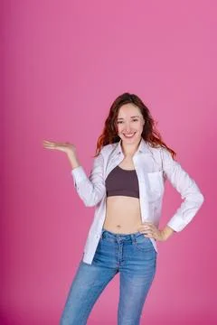 Smiling redhead presenting on a pink backdrop. Foto stock