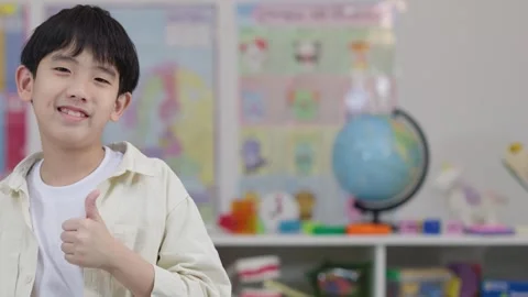 Smiling Schoolboy Giving Thumbs Up in Classroom 스톡 동영상 324934216