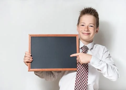 Smiling schoolboy pointing finger at empty chalkboard Stock Photos