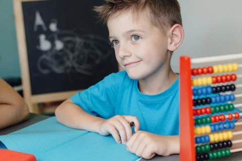 Smiling schoolboy working on math homework with an abacus Stock Photos