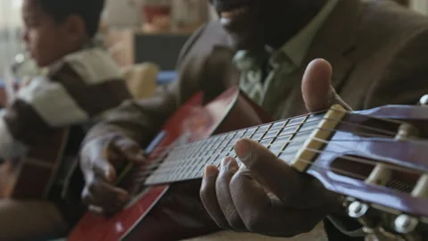 Smiling Senior Black Man Playing Guitar while Babysitting Grandson Video stock 322523803