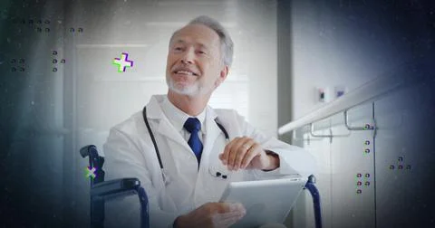 Smiling senior Dr holding tablet sitting wheelchair in clinic labcoat steth Stock Photos