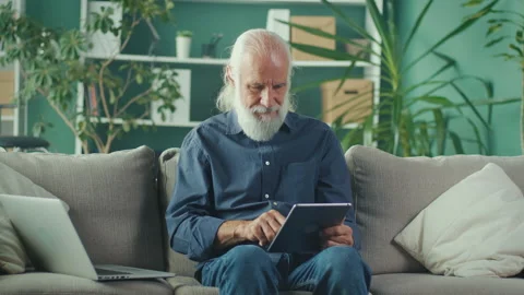 Smiling Senior Elder Man Using Tablet Computer Pad and Laptop and Relax Stock Footage 196253085