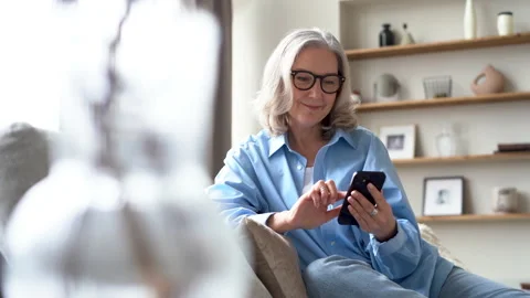 Smiling senior lady using smartphone texting message, enjoying communication Stock Footage 194950837
