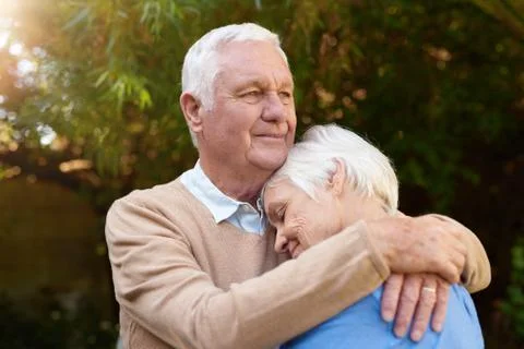 Smiling senior man affectionately hugging his wife outside Stock Photos