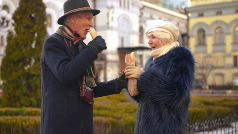 Smiling senior man breaking bread sharing with woman eating tasty bakery Stock Footage 229867370
