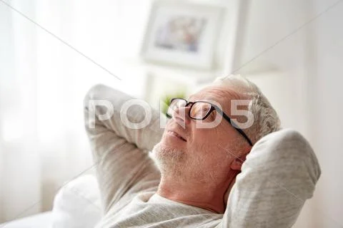 Smiling senior man in glasses relaxing on sofa Stock Photos