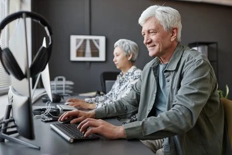 Smiling senior man using computer in class for elderly people Stock Photos