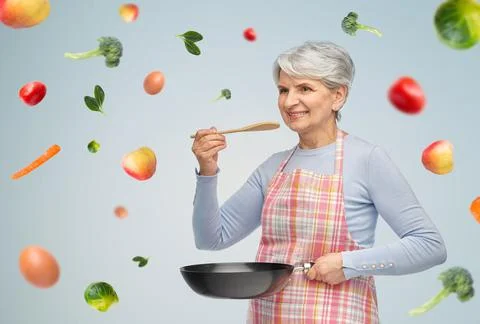 Smiling senior woman in apron with frying pan Stock Photos