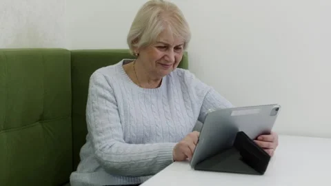 Smiling senior woman using tablet at table, digital lifestyle Stock Footage 328533143