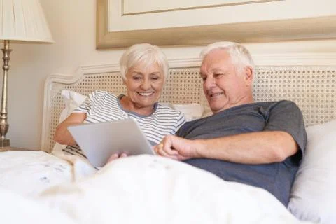 Smiling seniors using a digital tablet together in bed Stock Photos
