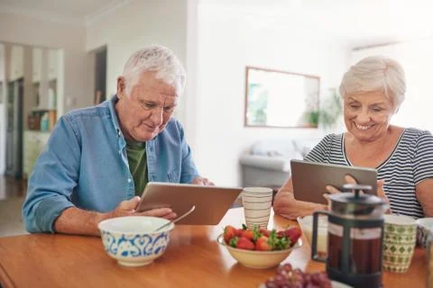 Smiling seniors using digital tablets over breakfast at home Stock Photos