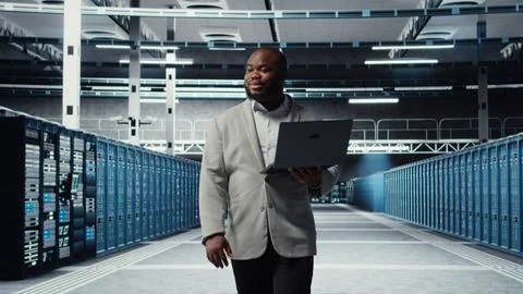 Smiling server room engineer performing maintenance on server racks Foto stock