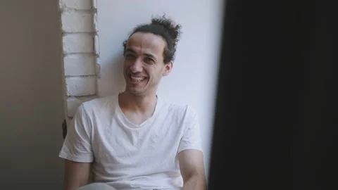 Smiling shy man sitting on window sill and smiling Video stock 158159608