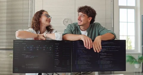 Smiling Software Developers Collaborating Behind Monitors in Coding Office Stock Footage 345880212