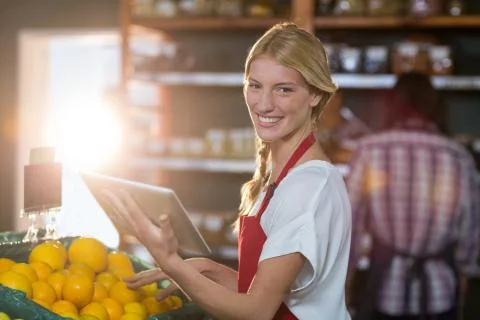 Smiling staff using digital tablet while checking fruits in organic section Stock Photos