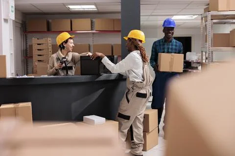 Smiling storehouse operators chatting at reception desk doing inventory 写真素材