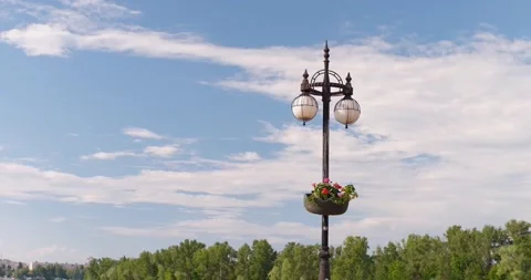Smiling street lighting lantern in the shape of a face with flowers. A girl pass Stock Footage 246449313