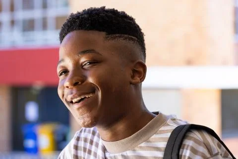 Smiling student with backpack enjoying time outside school building Fotos de archivo