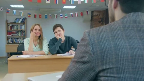 Smiling student giving answer in class with her hand raised Vídeos de archivo 77509595