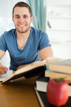 Smiling student with his assignment in front of him Stock Photos