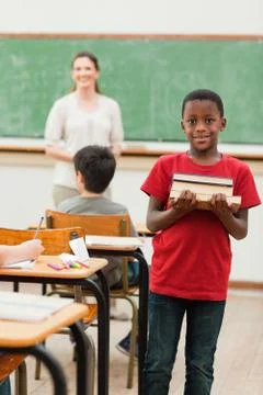 Smiling student holding stack of books Fotos Stock